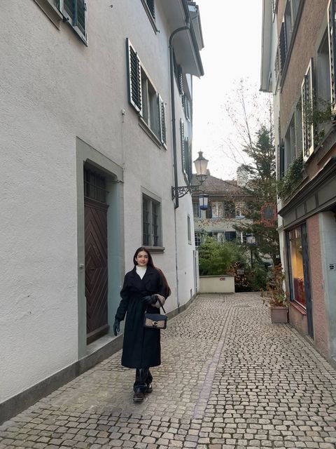 Shrestha Dutta walking through a cobblestone alley in old-town Geneva, Switzerland